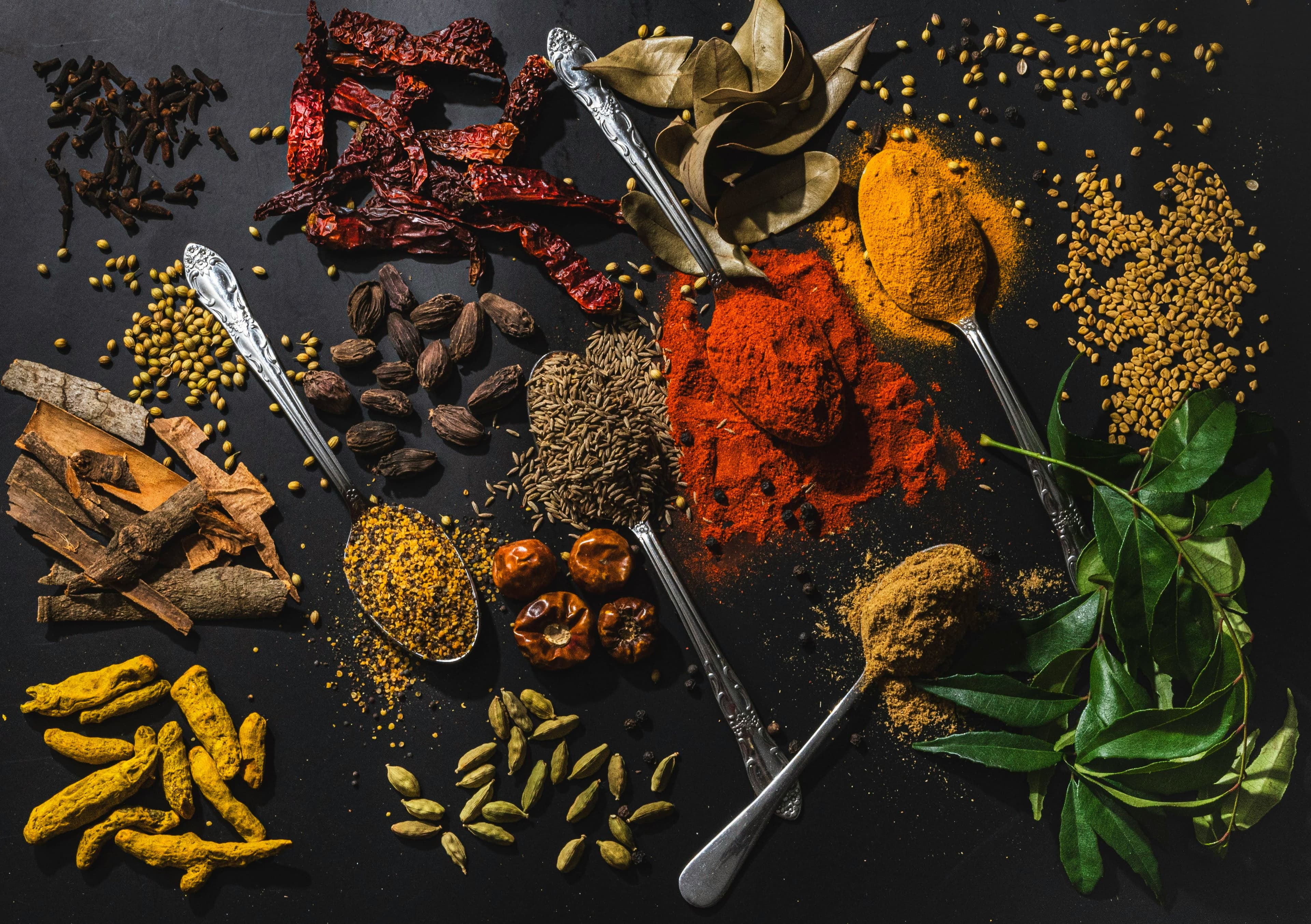 Spice flat-lay — cinnamon, turmeric, paprika, cardamom and curry leaves, the heart of every African recipe